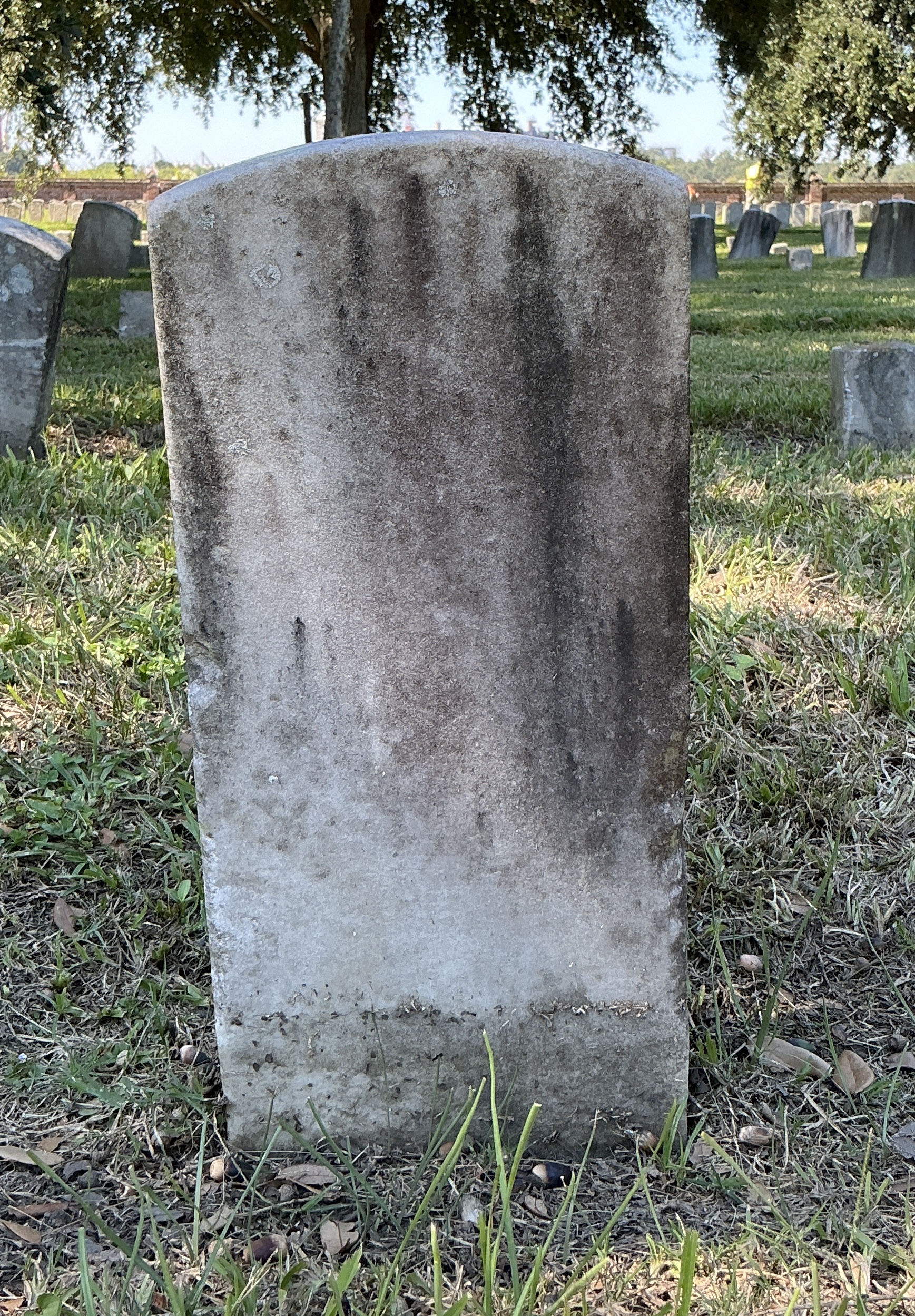 Back of historic upright marble headstone with recessed shield face.