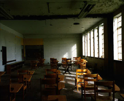 wooden desks in a dimly lit rundown classroom