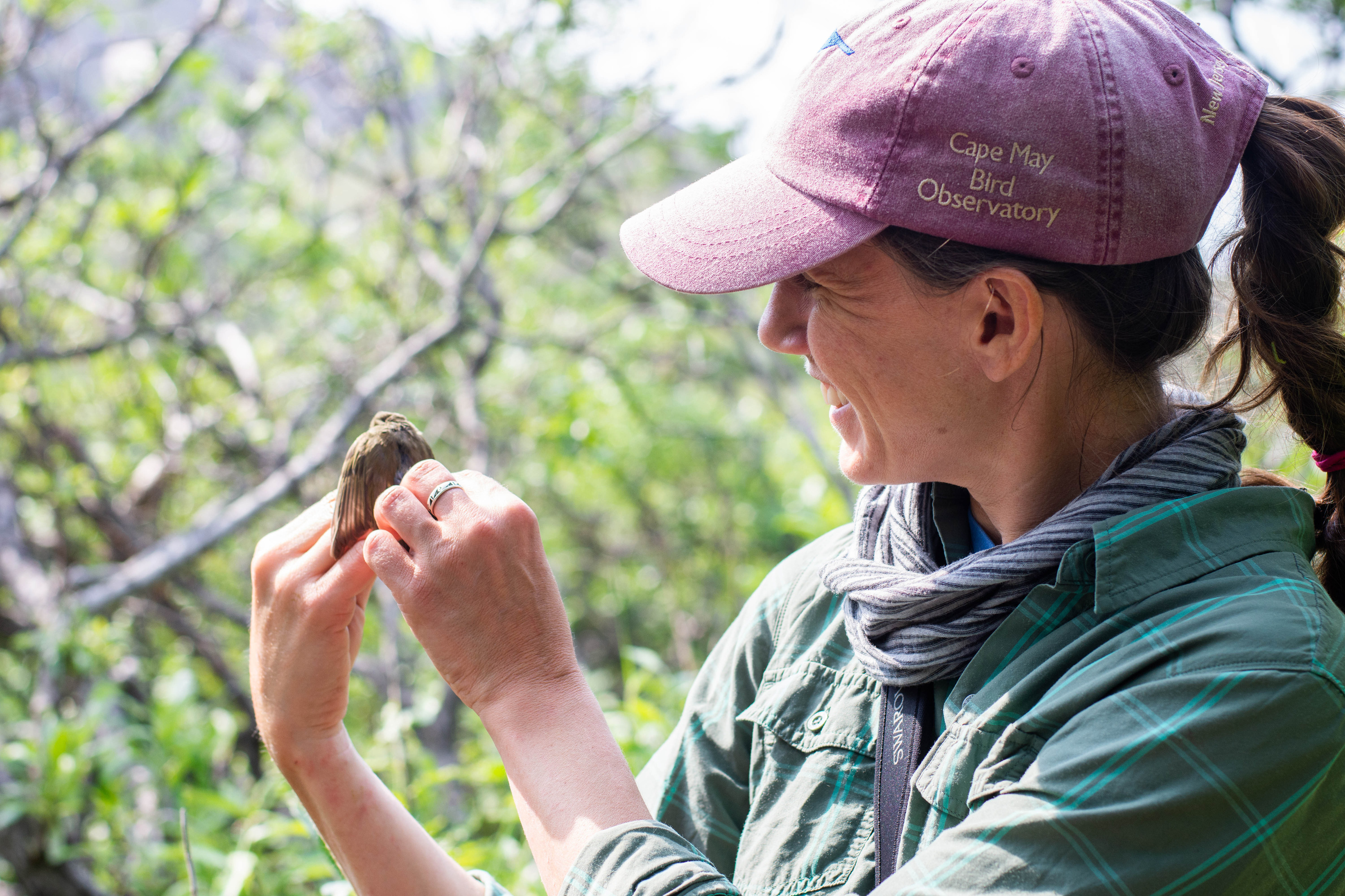 a woman smiling while holding a small bird in her hand