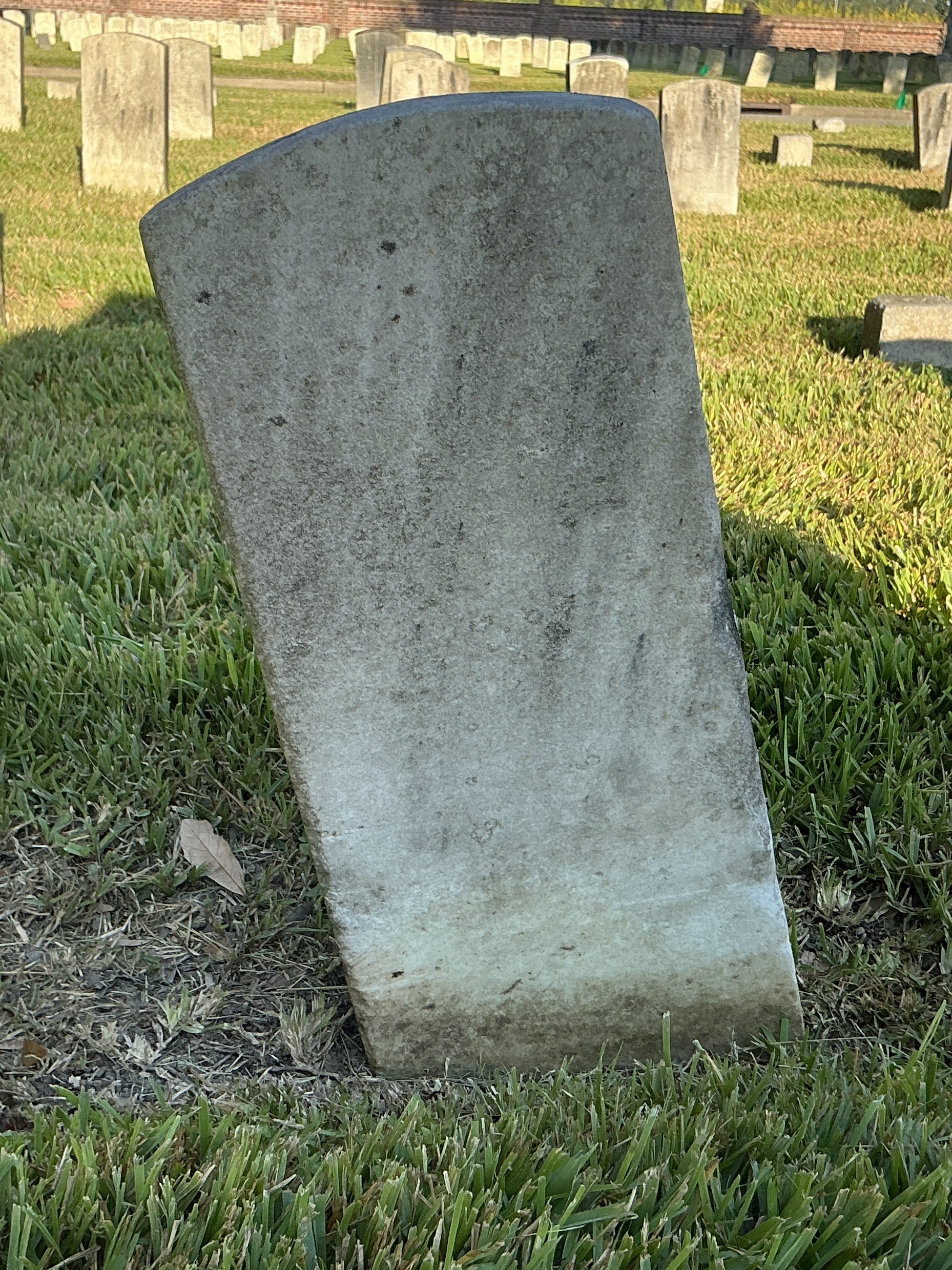 Back of historic upright marble headstone with recessed shield face.
