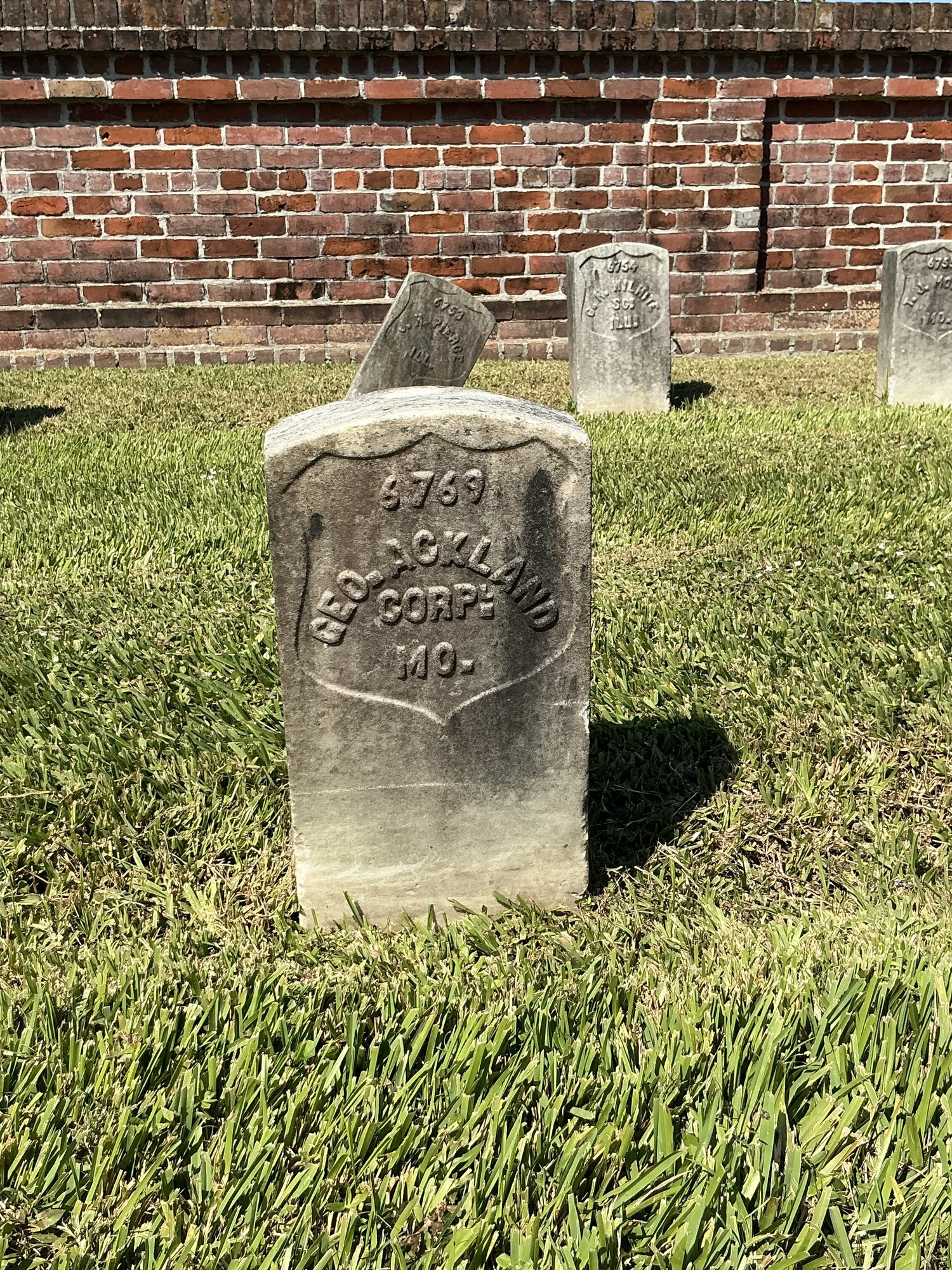 Front of historic upright marble headstone with recessed shield face.