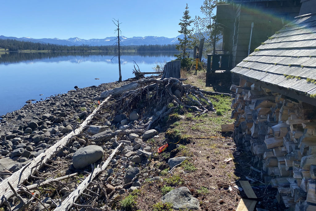 A cabin near a lake shore that is rocky and eroded.