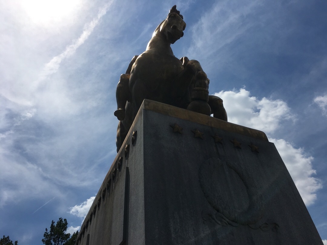 A bronze statue of a man riding a horse on top of a granite podium