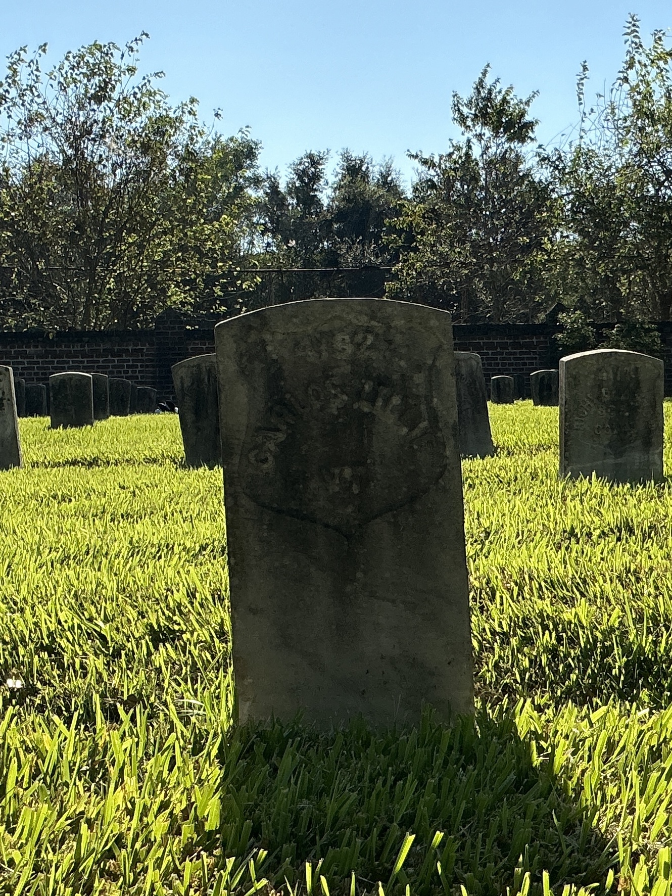 Front of historic upright marble headstone with recessed shield face.