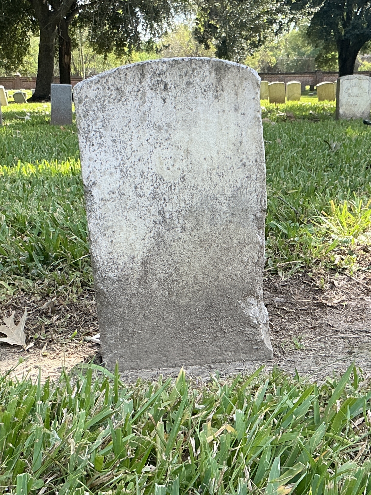 Back of historic upright marble headstone with recessed shield face.
