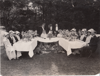 Madeleine Edison and John Eyre Sloane sitting at table with members of their wedding party.