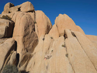 A person curled up on a rock blends into the larger rock formation.