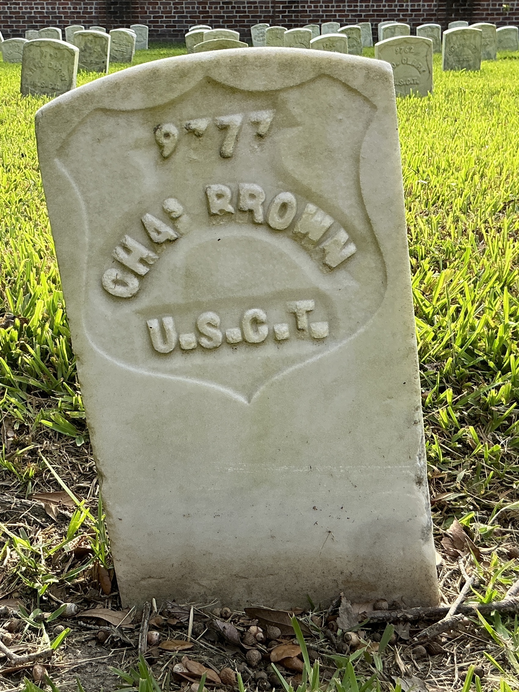 Front of historic upright marble headstone with recessed shield with recessed lettering face.