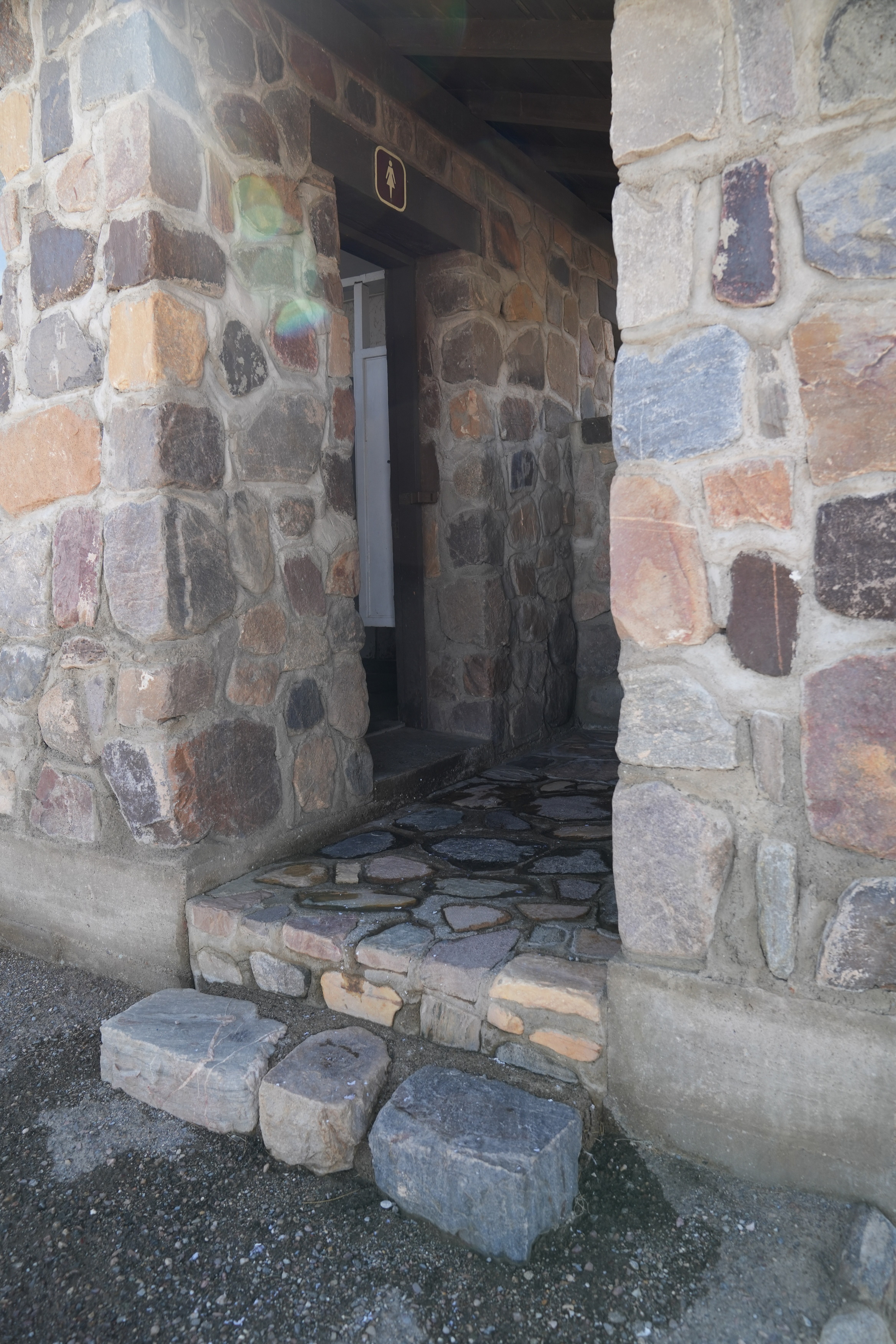 Emigrant Rest Stop and Campground bathroom entrance. Gravel ground to cobblestone step and another step shortly after.