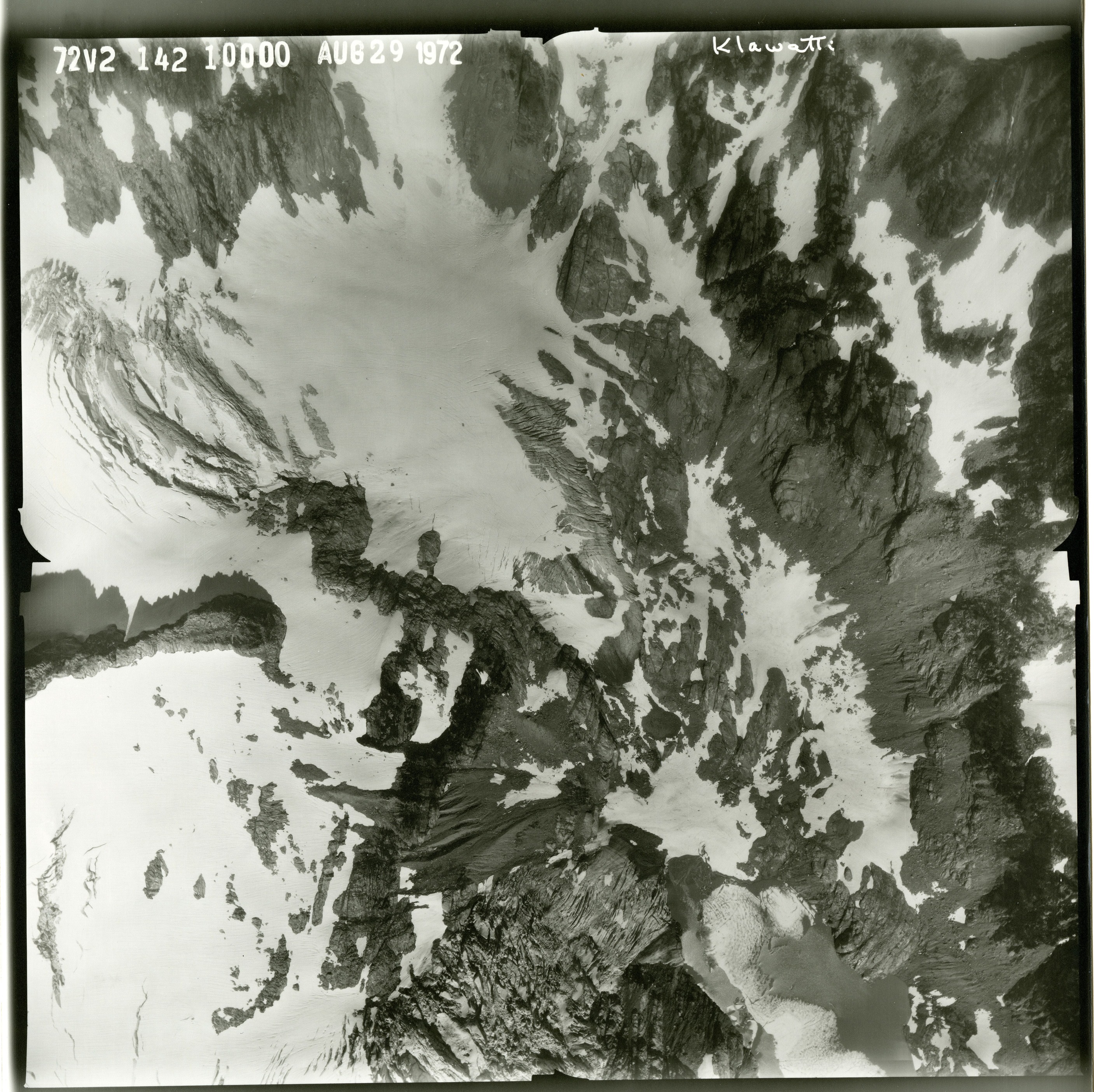 Black and white aerial photograph of glacier on mountain peak.