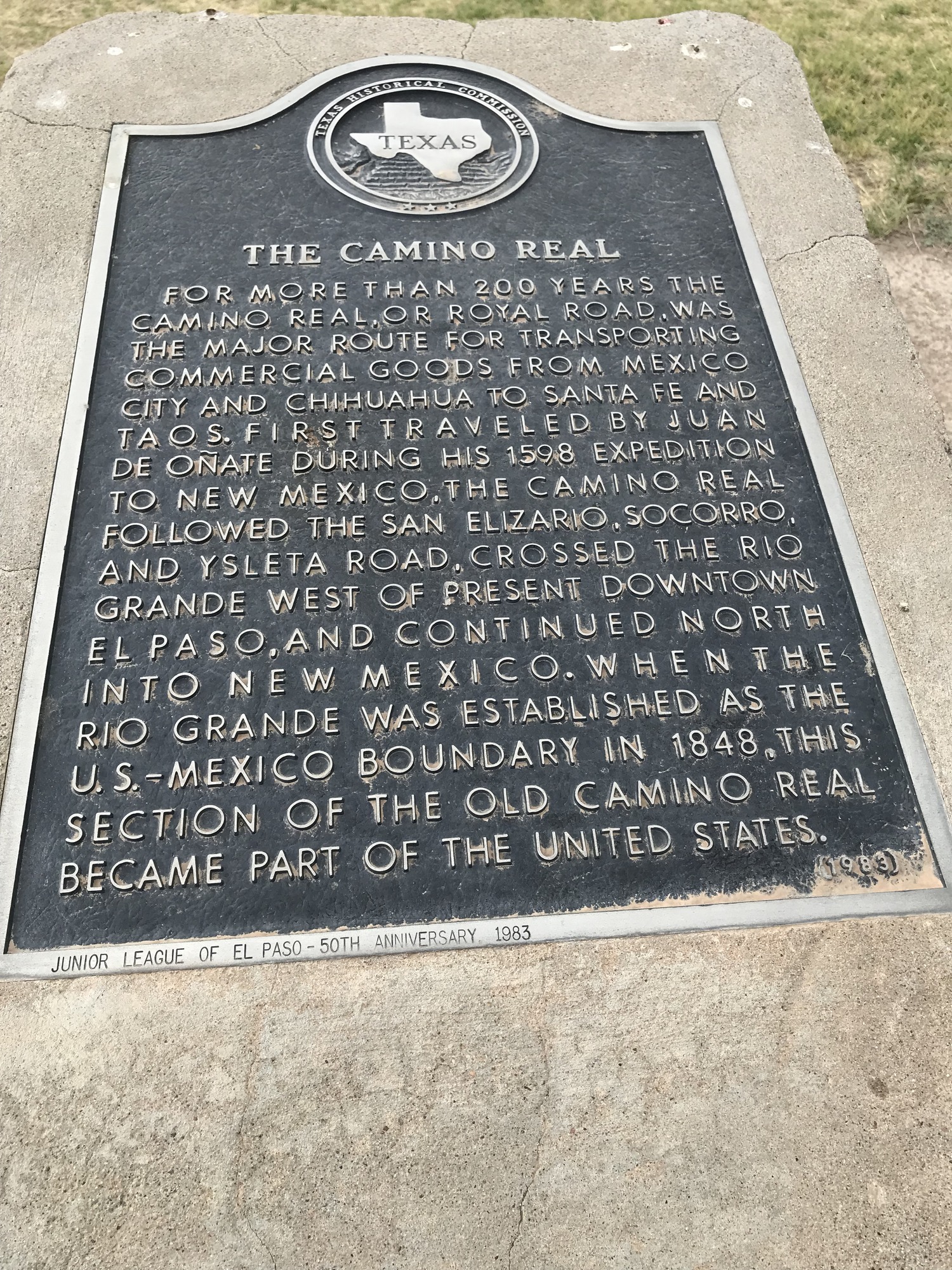 A plaque with information on it in front of a grassy area.
