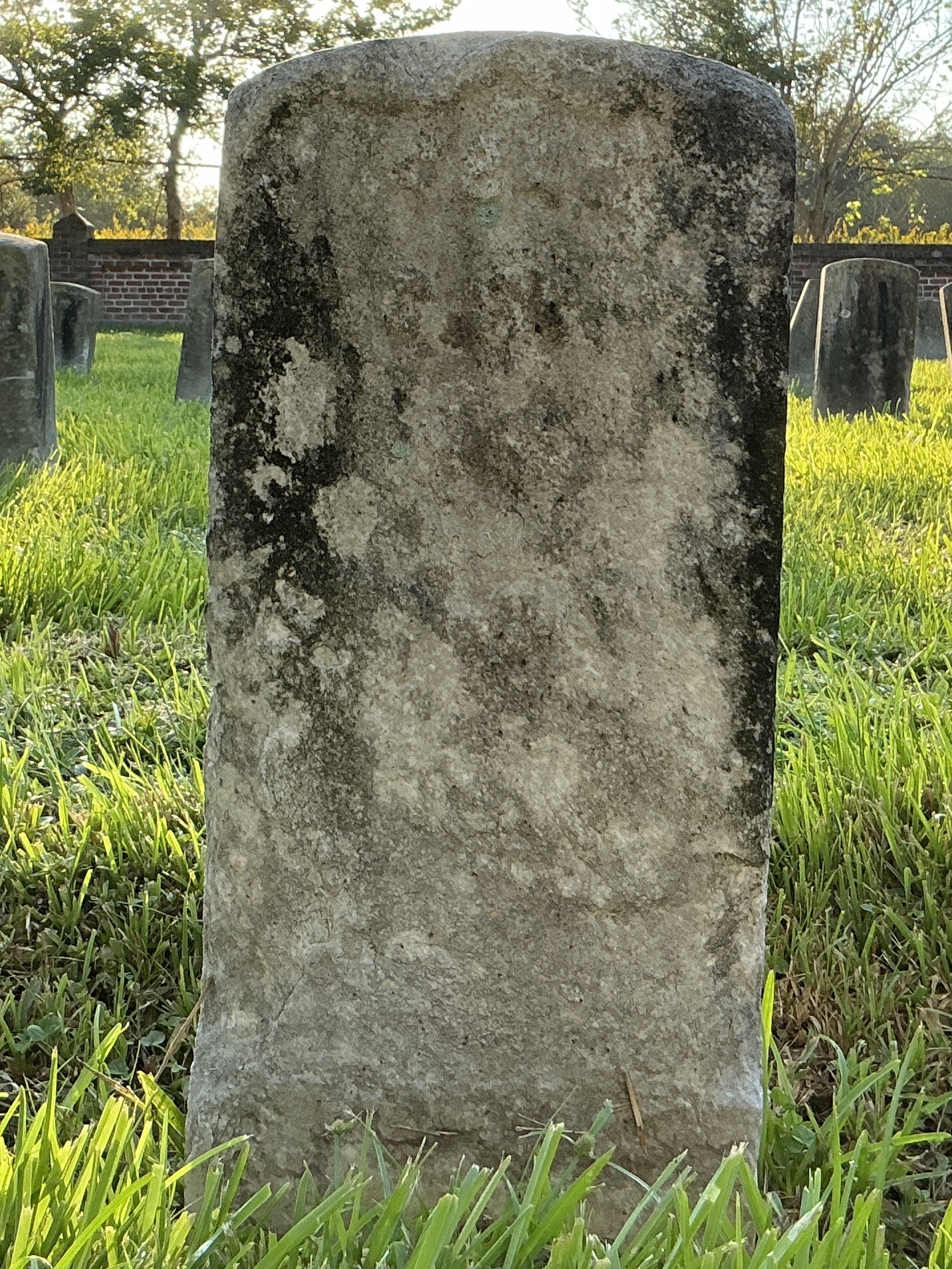 Front of historic upright marble headstone with recessed shield face.