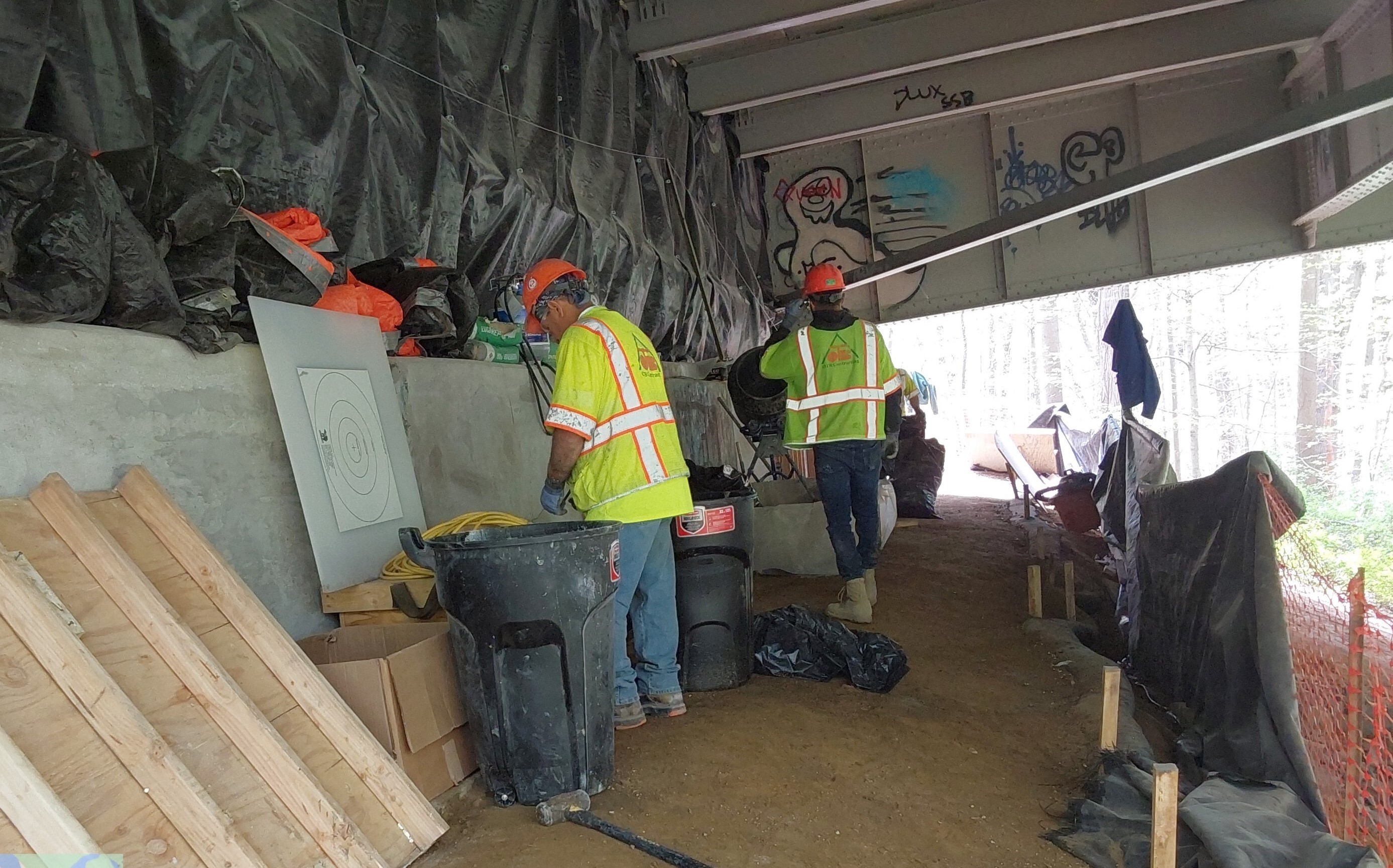 Workers underneath a bridge.