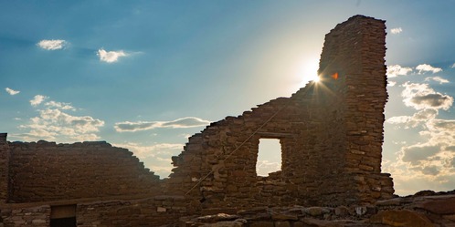 A wall of Pueblo Bonito with the sun illuminating it from behind.