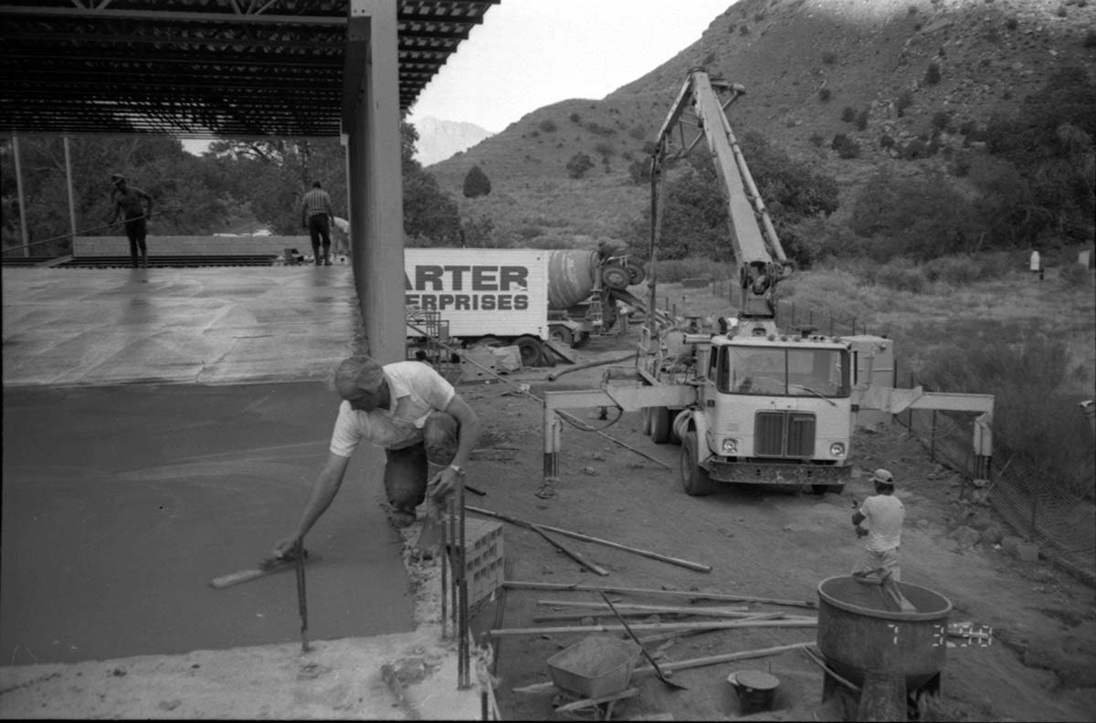 Man leveling cement in corner during construction of headquarters addition.