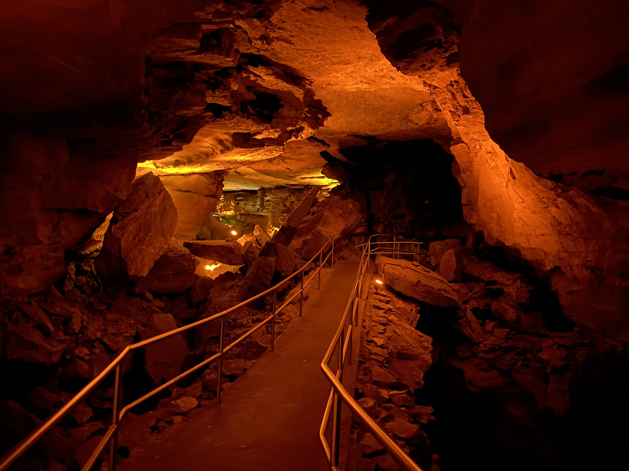 A narrow cave trail lined with handrails on each side. 
