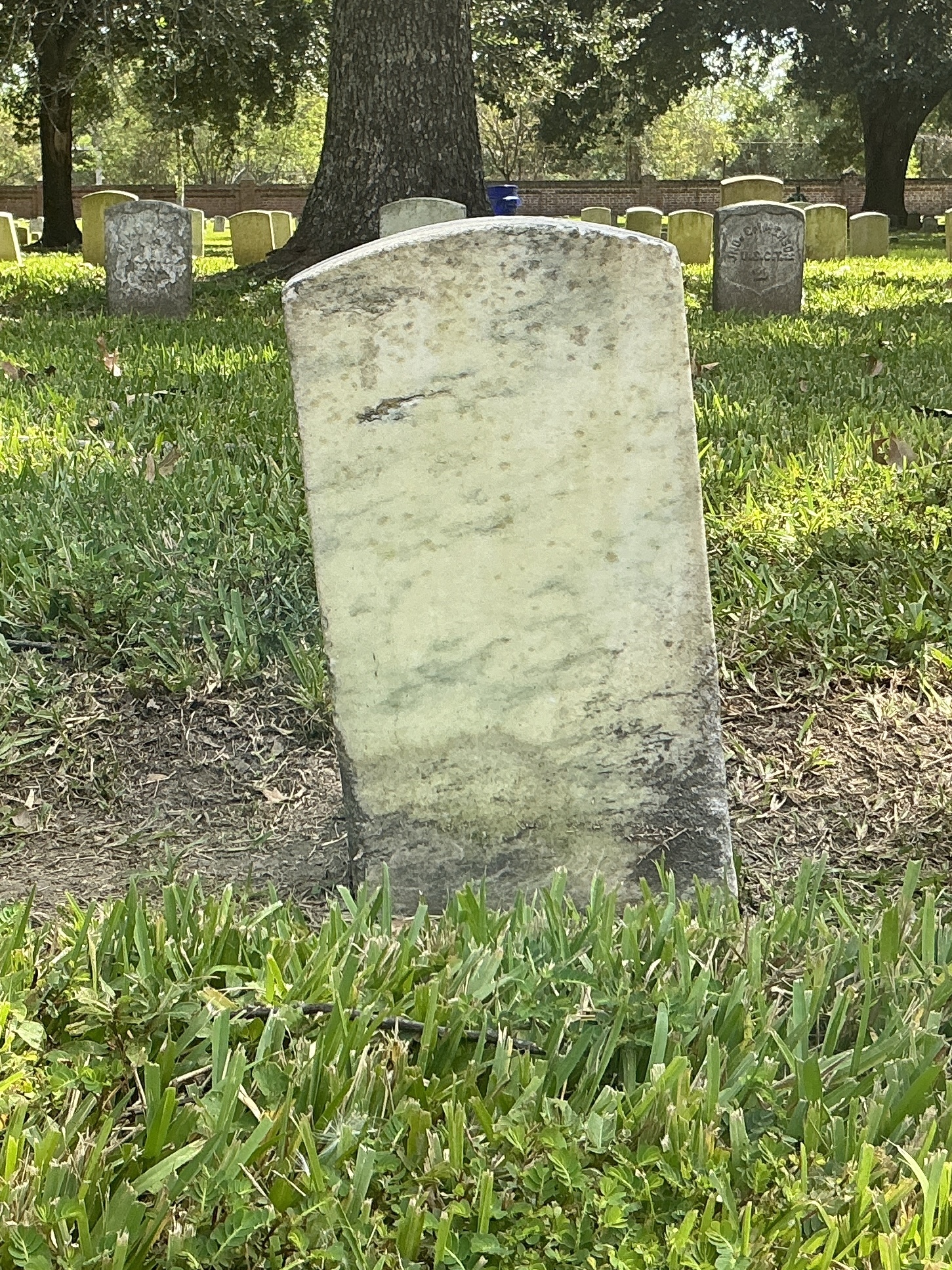 Back of historic upright marble headstone with recessed shield face.