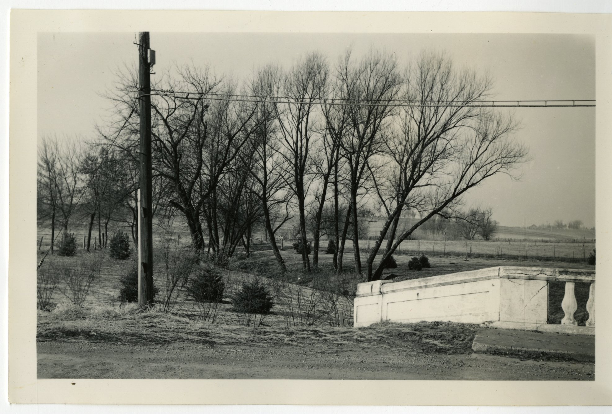 A 1940 era photo shows a bridge abutment and telephone pole at the edge of a creek bed.