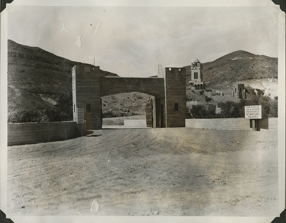 This is an historic black and white photograph from the Scotty's Castle Historic Photograph Collection, Death Valley National Park of Scotty's Castle Entrance Gate with a signs posted on each side: The Castle Is Closed Positively No Admittance Scotty. Circa 1931. Photographed by Mat Roy Thompson.