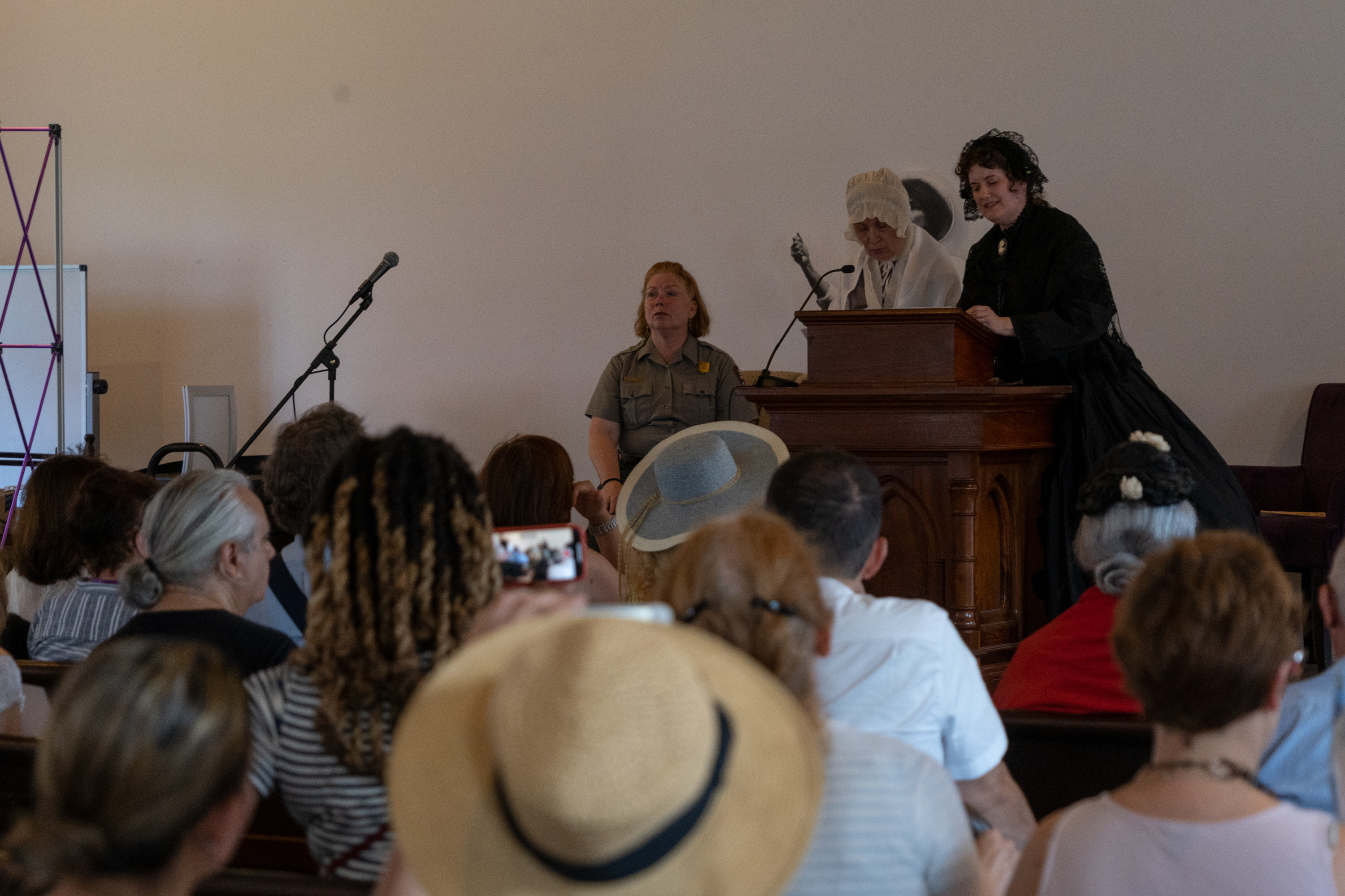 Living historians speak to an audience from a pulpit.