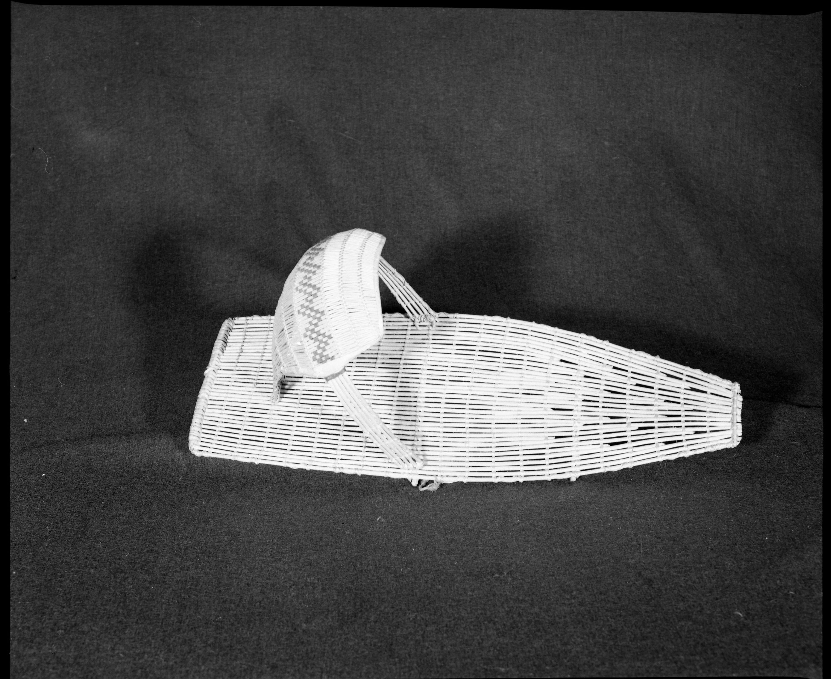 Marie Rozier Collection, Catalog No. 37. Object: Washoe/Paiute cradle basket. Dimensions: 22 x 8". Materials: Willow, cotton cloth, yarn. Technology: Plain twined backboard, diagonally twined hood, down to right slant of turns. Collection History: From Bridgeport, cost $10 at Ella Cane's store. Purchased in early 1950s. Photographed by Michael Dixon, December 1982. Catalogued by Craig Bates and Barbara Beroza. Yosemite Collections, National Park Service.