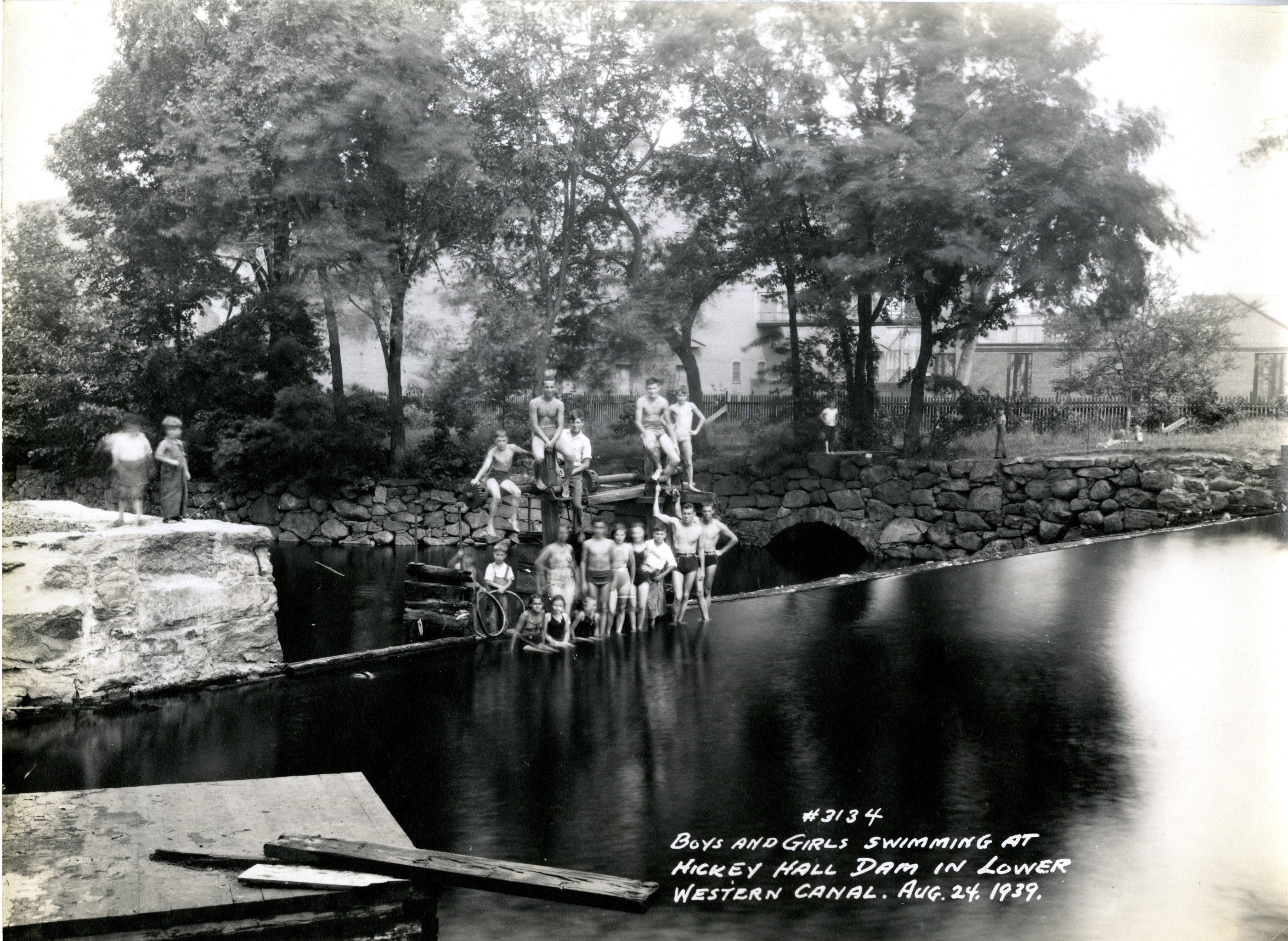 A photo showing a large group of children and teens poses for the camera atop the gate hoisting platform.