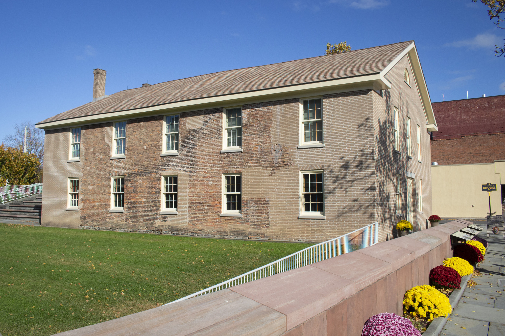 An exterior view of the Wesleyan Chapel, a light brown brick building with flowers out front.