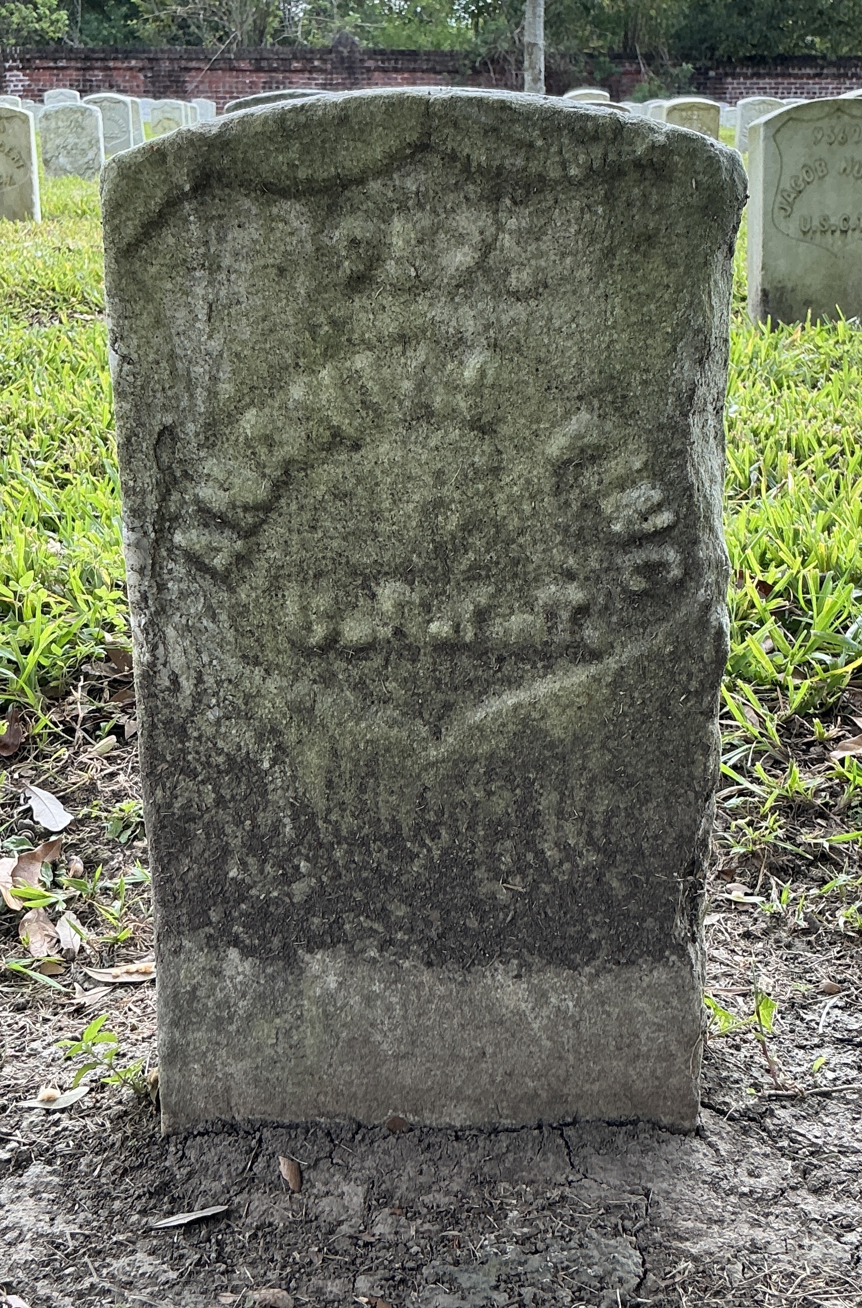 Front of historic upright marble headstone with recessed shield face.