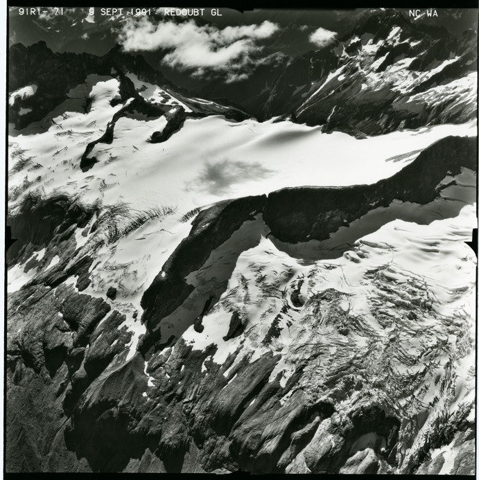 Black and white aerial photograph of glaciated mountain peaks and valleys.
