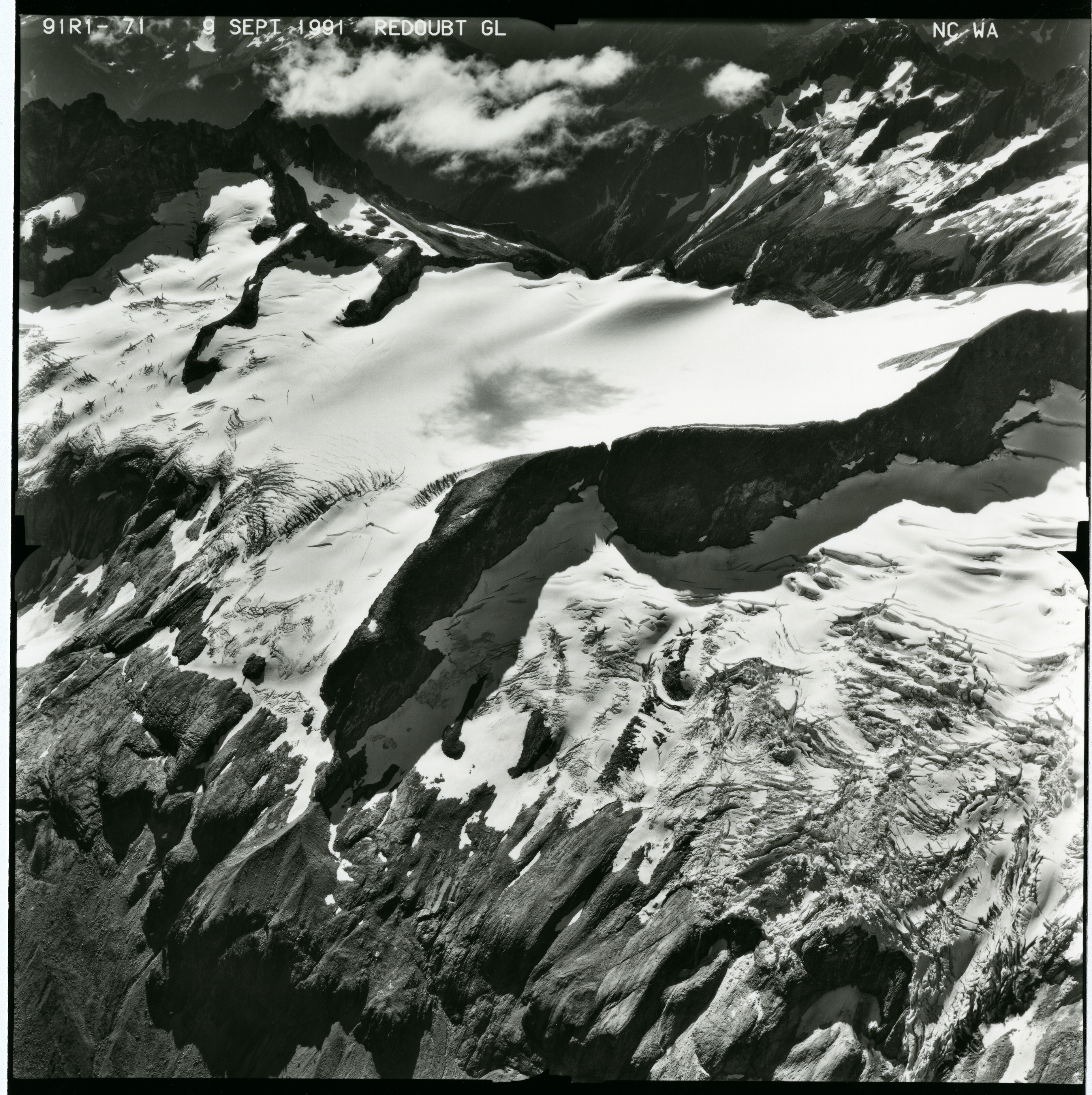 Black and white aerial photograph of glaciated mountain peaks and valleys.