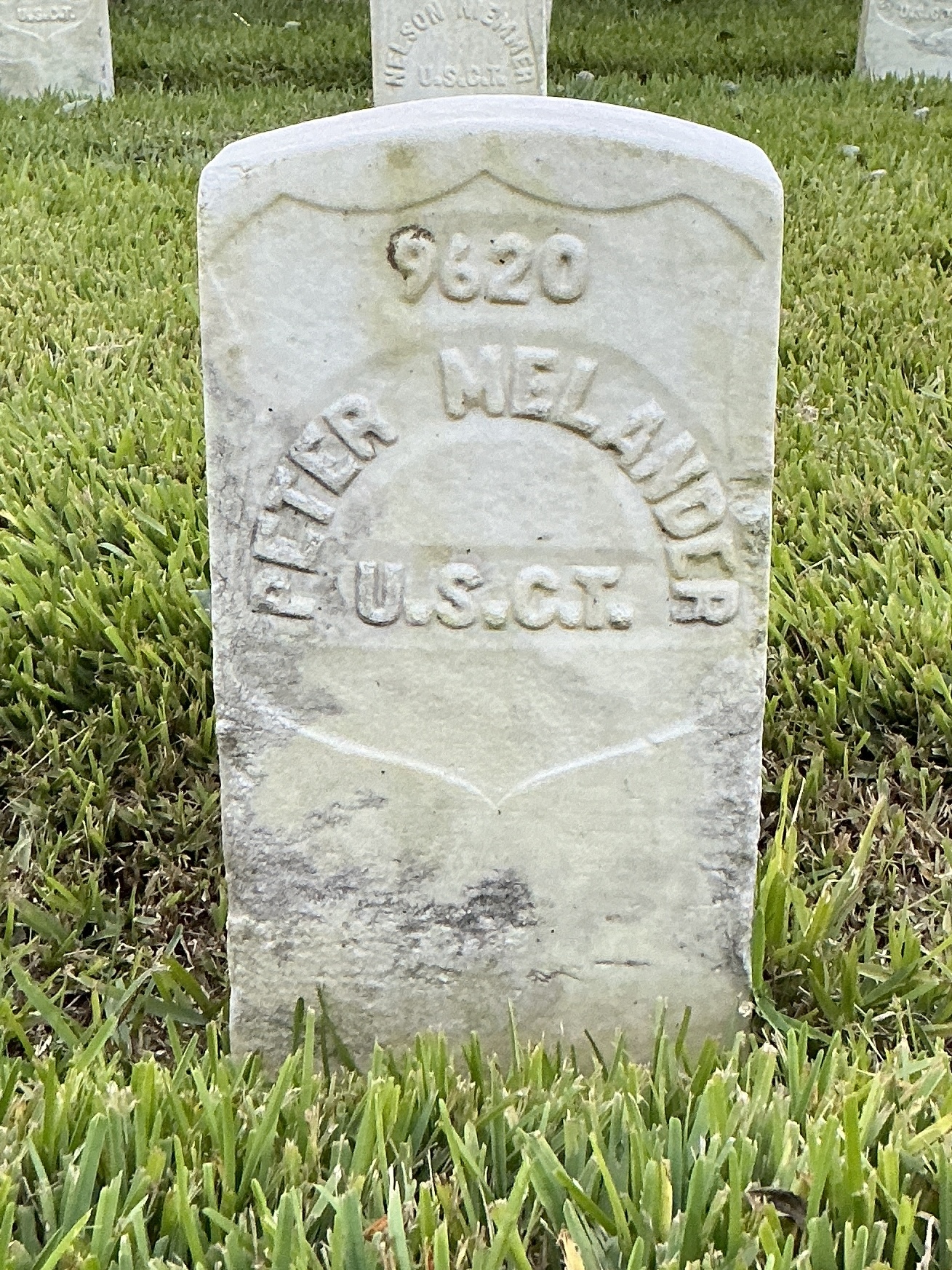 Front of historic upright marble headstone with recessed shield face.