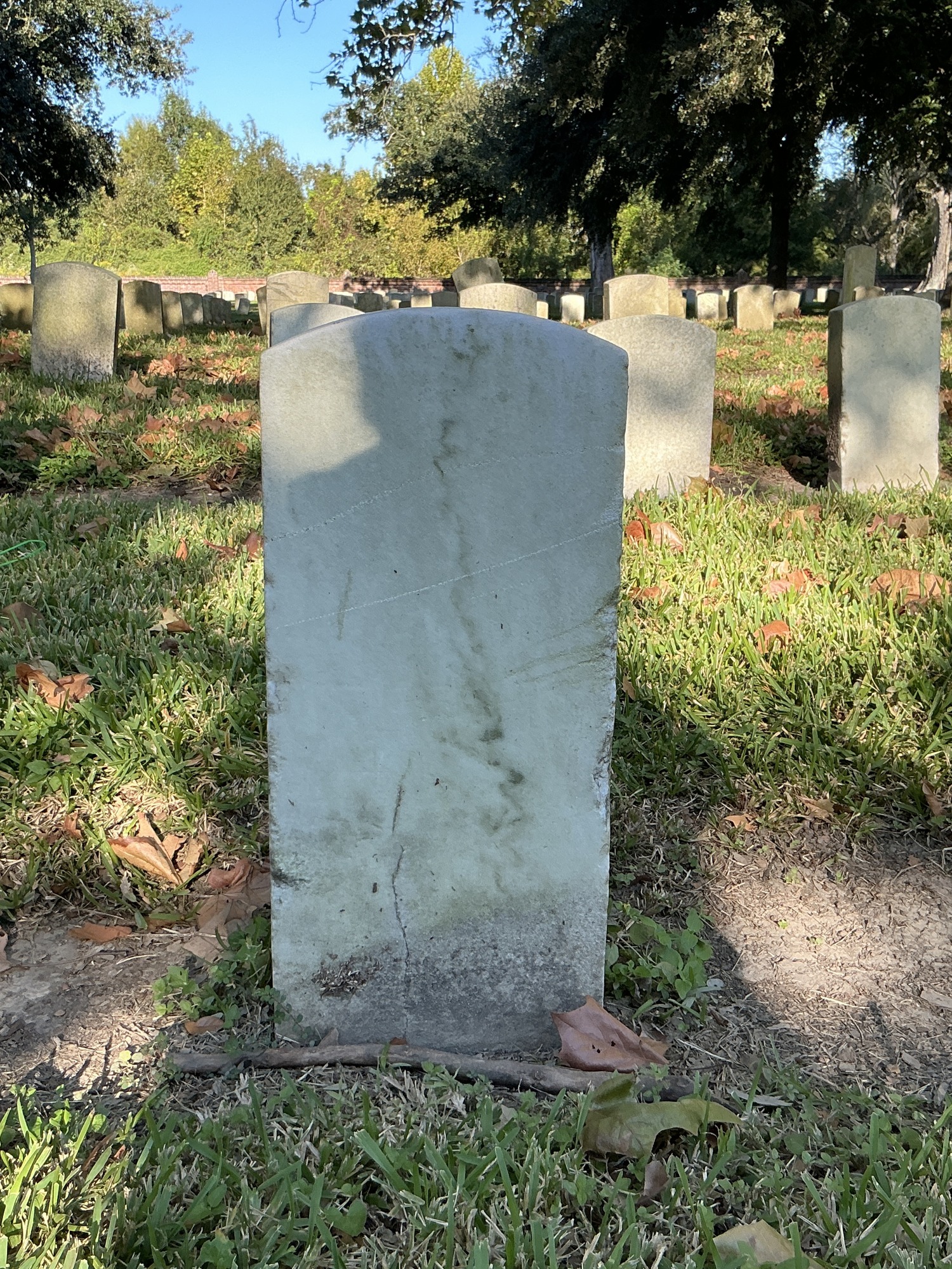 Back of historic upright marble headstone with recessed shield face.