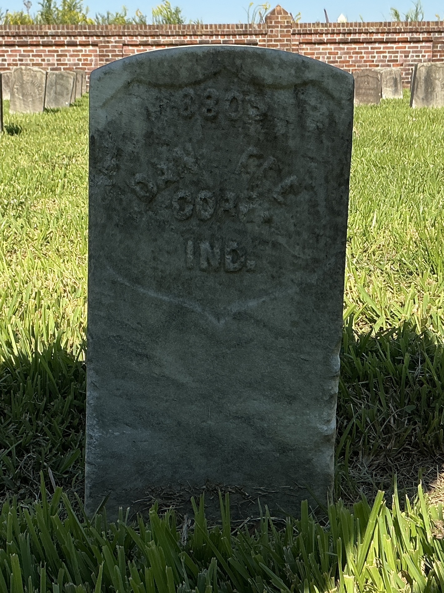 Front of historic upright marble headstone with recessed shield face.
