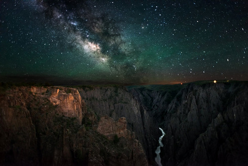 A star-filled night sky frames this dramatic view of rocky cliffs and gorge at Black Canyon of the Gunnison National Park, Colorado.