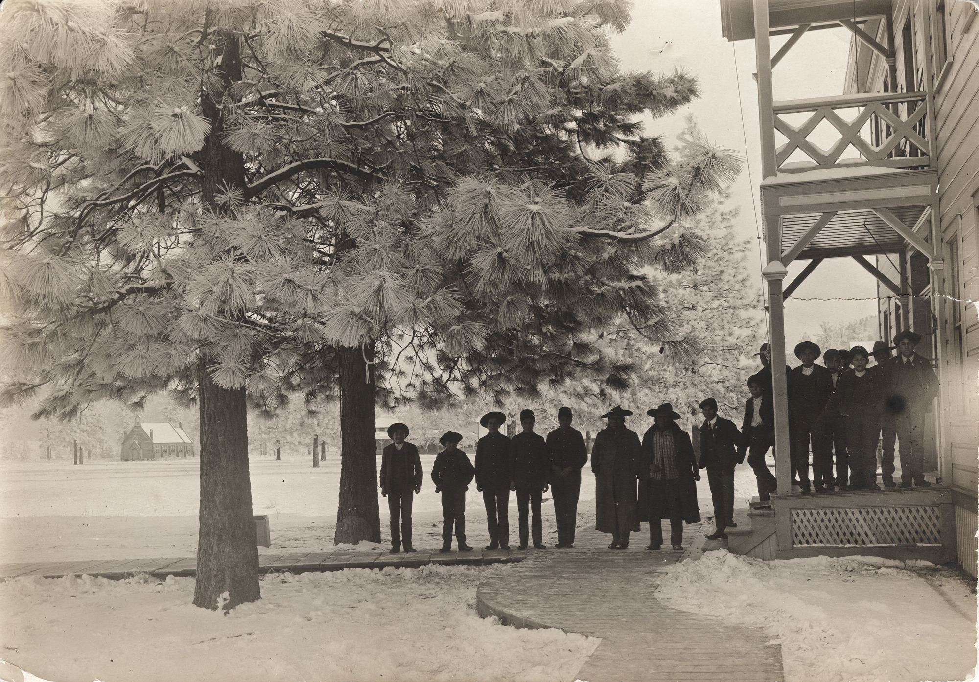 Black and white photograph of people standing outside a building among trees