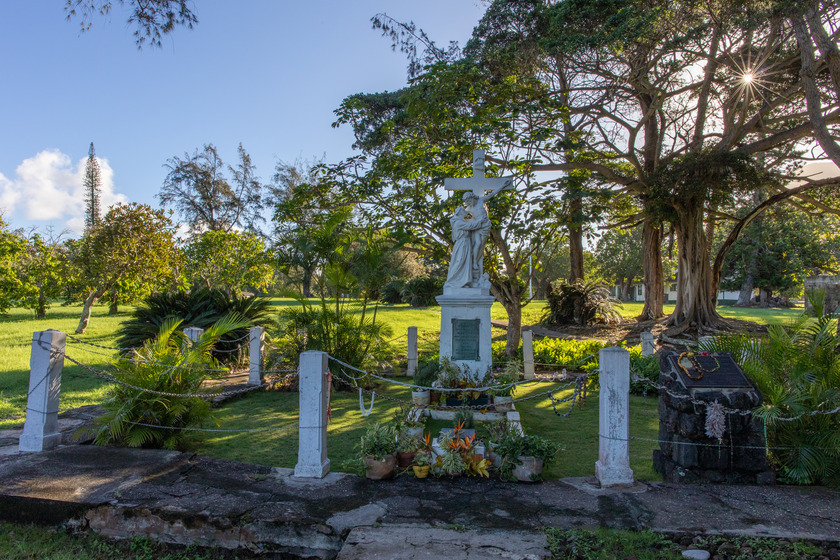 An ornate grave site with a statue and plants.