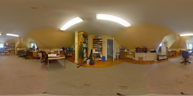 a panorama of a room with a dingy beige carpet, yellow walls and florescent lights