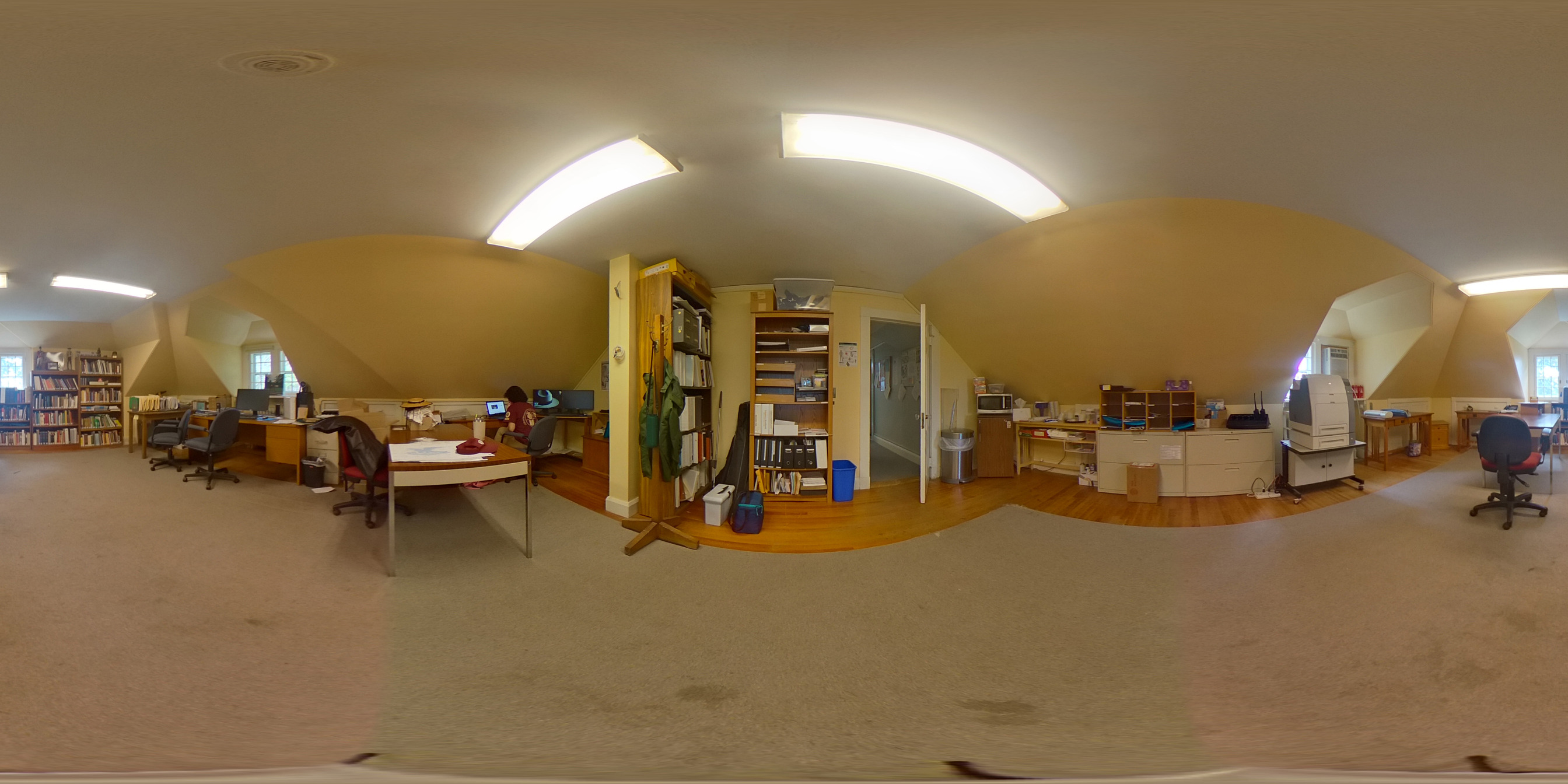 a panorama of a room with a dingy beige carpet, yellow walls and florescent lights
