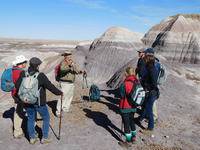 Uniformed man on a badland hike with other people under a blue sky.