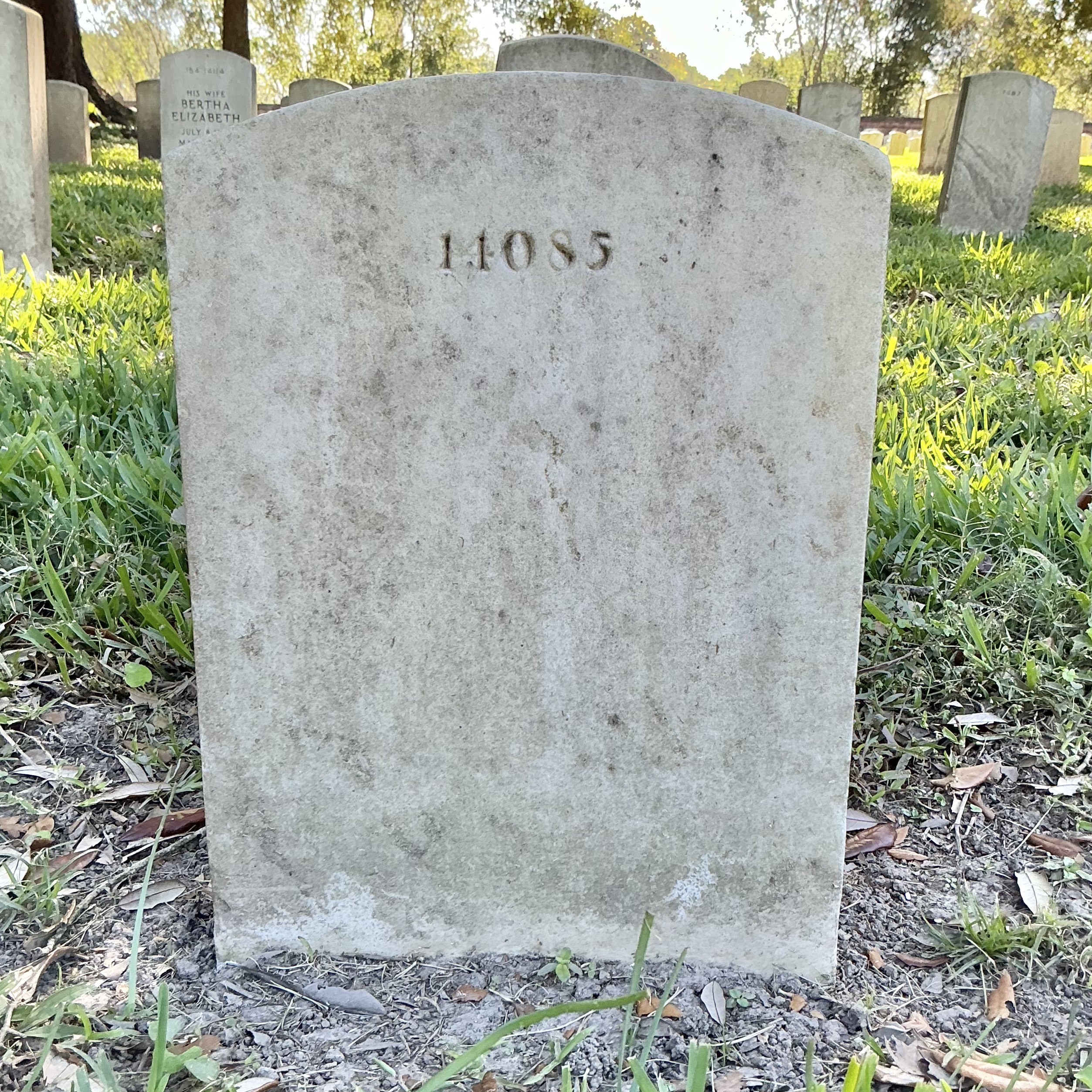 Back of historic upright marble headstone with recessed shield face.