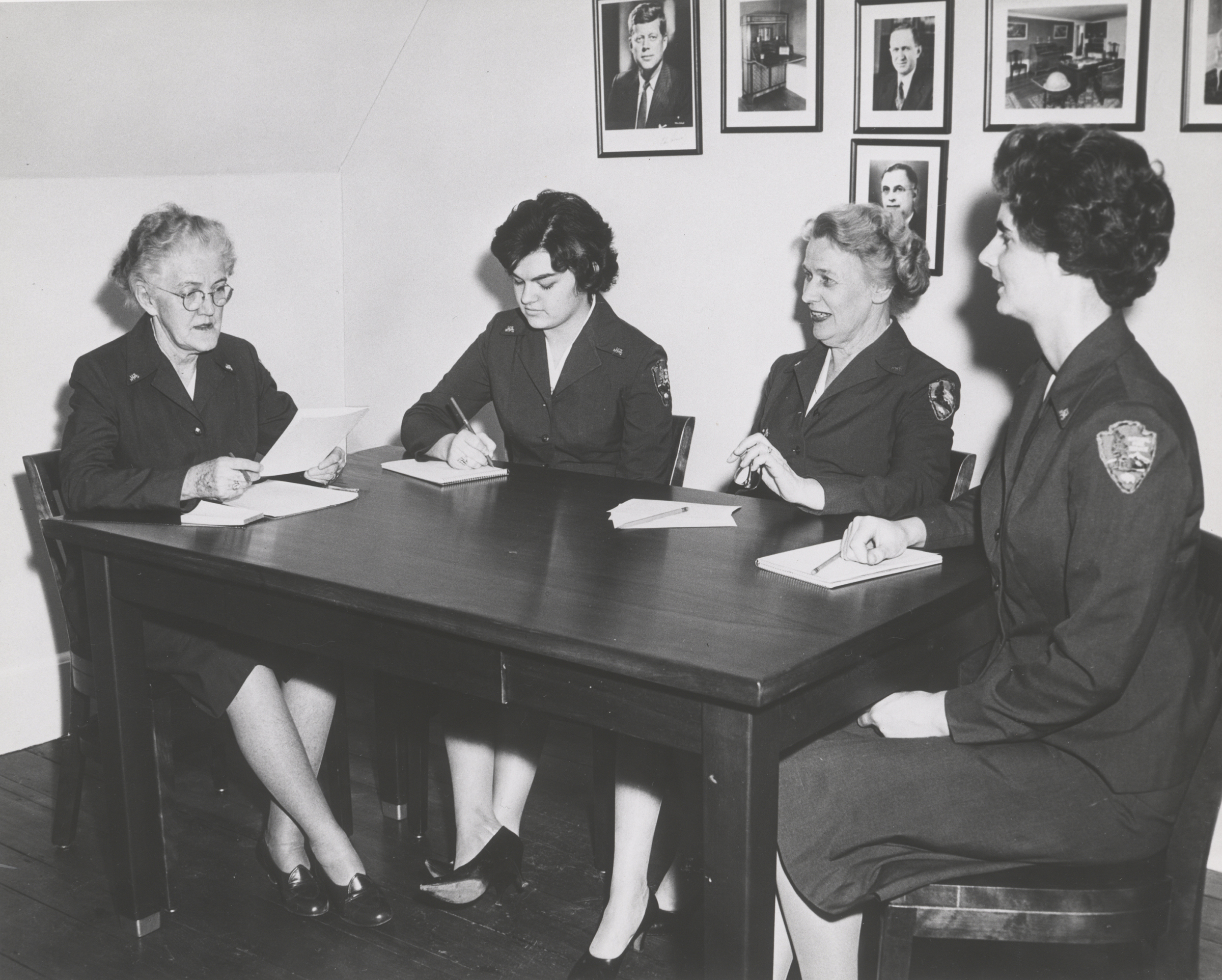 Wilhelmina Harris, Marianne Potts, Anne Boyes, and Helen Nelson wear NPS uniforms and sit at a table.