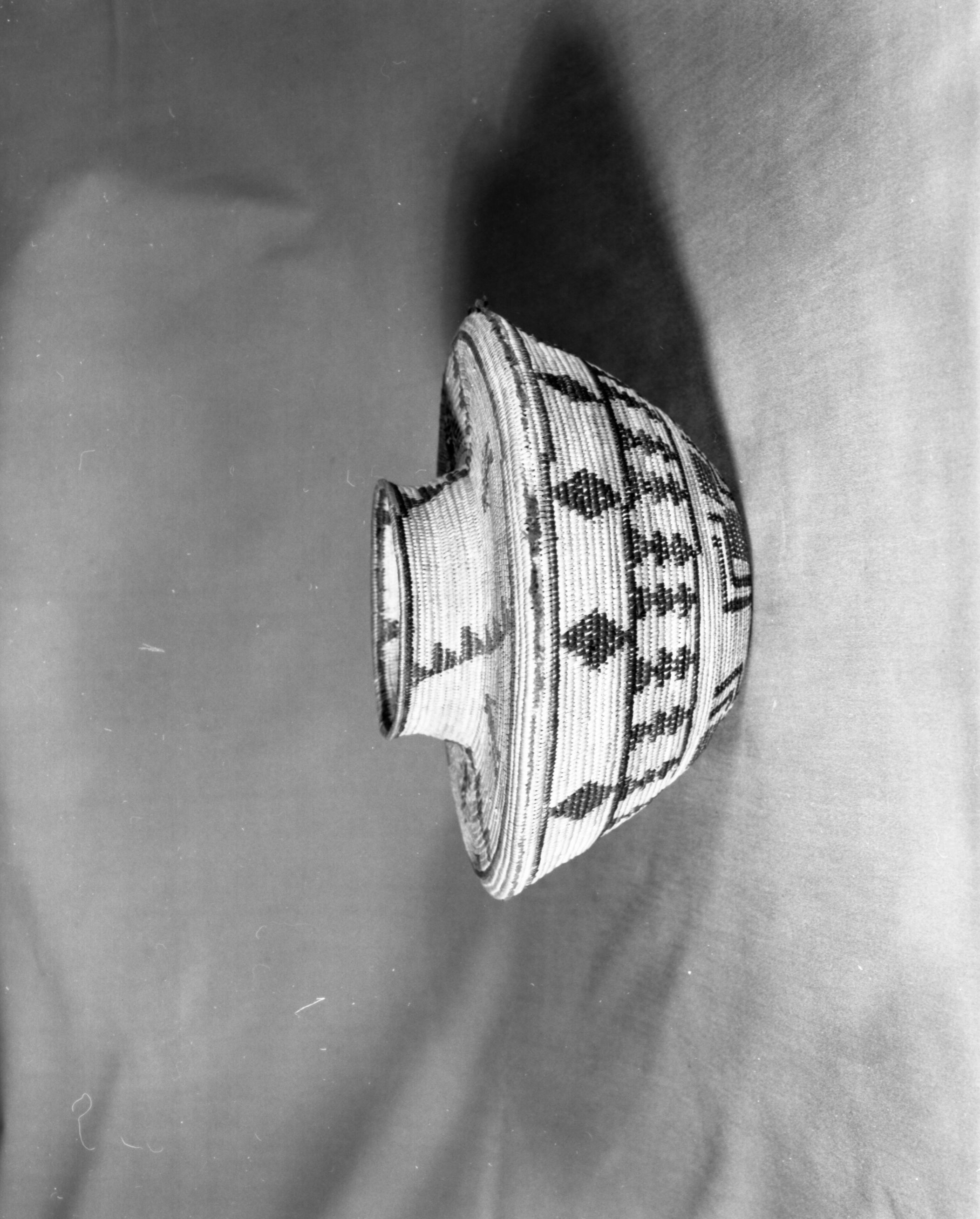 Private Collection. Object: Yokuts basket purchased from a Miwok. Dimensions: 6 1/4" height 10 1/4" diameter. Materials: Sedge root, fern root, redbud, bunch grass, red wool yarn, quail top knots. Technology: Right ward coil direction, outside work face, noninterlocking stitch, fag ends trimmed on work face, moving ends trimmed on interior, tight spiral start. Collection History: Purchased from Mrs. Mary Longfellow Poncho (Maggie Longfellow Antoninni's mother). Yokuts manufacture, probably obtained during her residence in Tulare County. Photographed by Michael Dixon. Catalogued by Craig Bates and Barbara Beroza. Yosemite Collections, National Park Service.