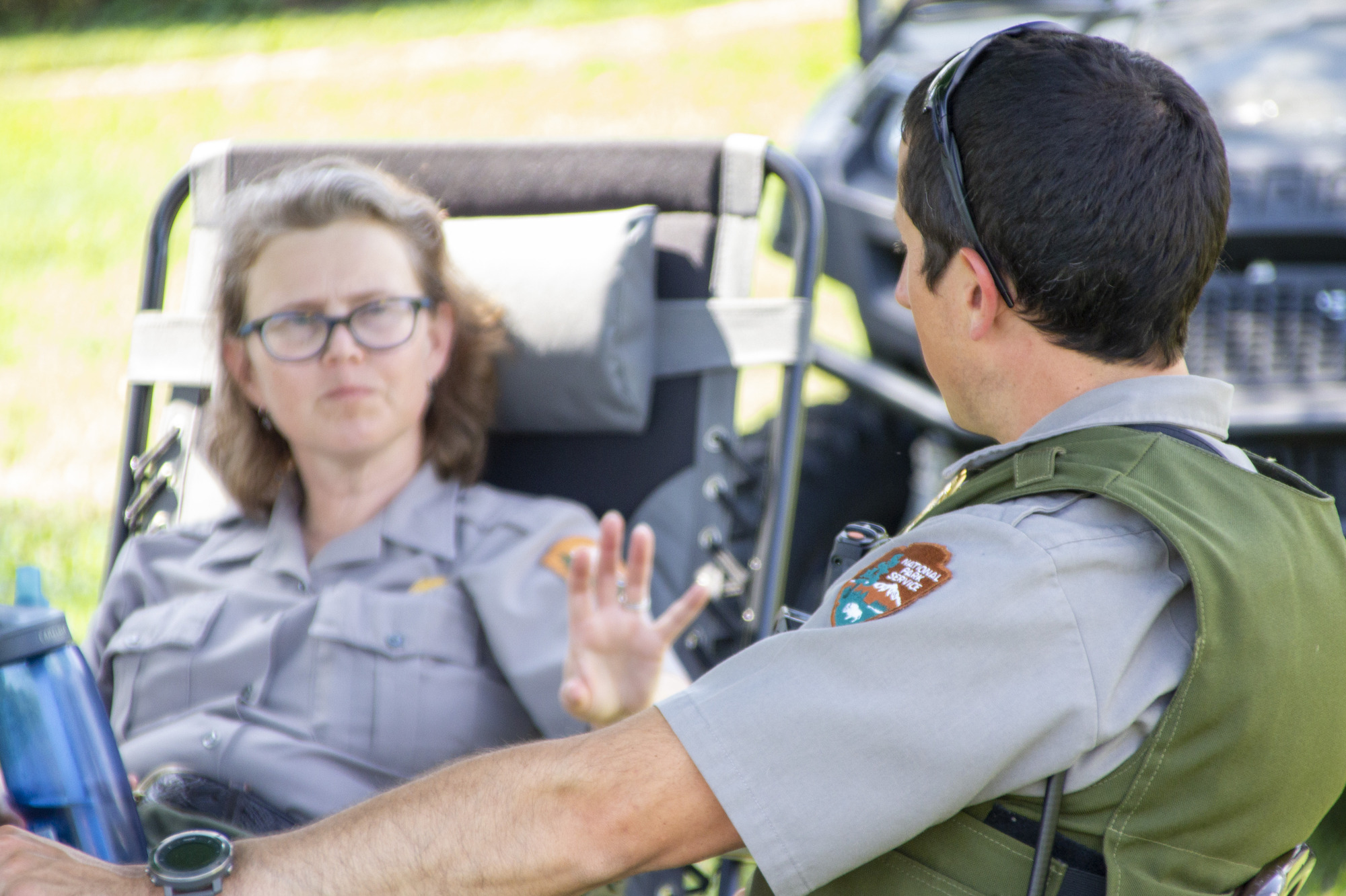 Two park rangers seating talking to one another.