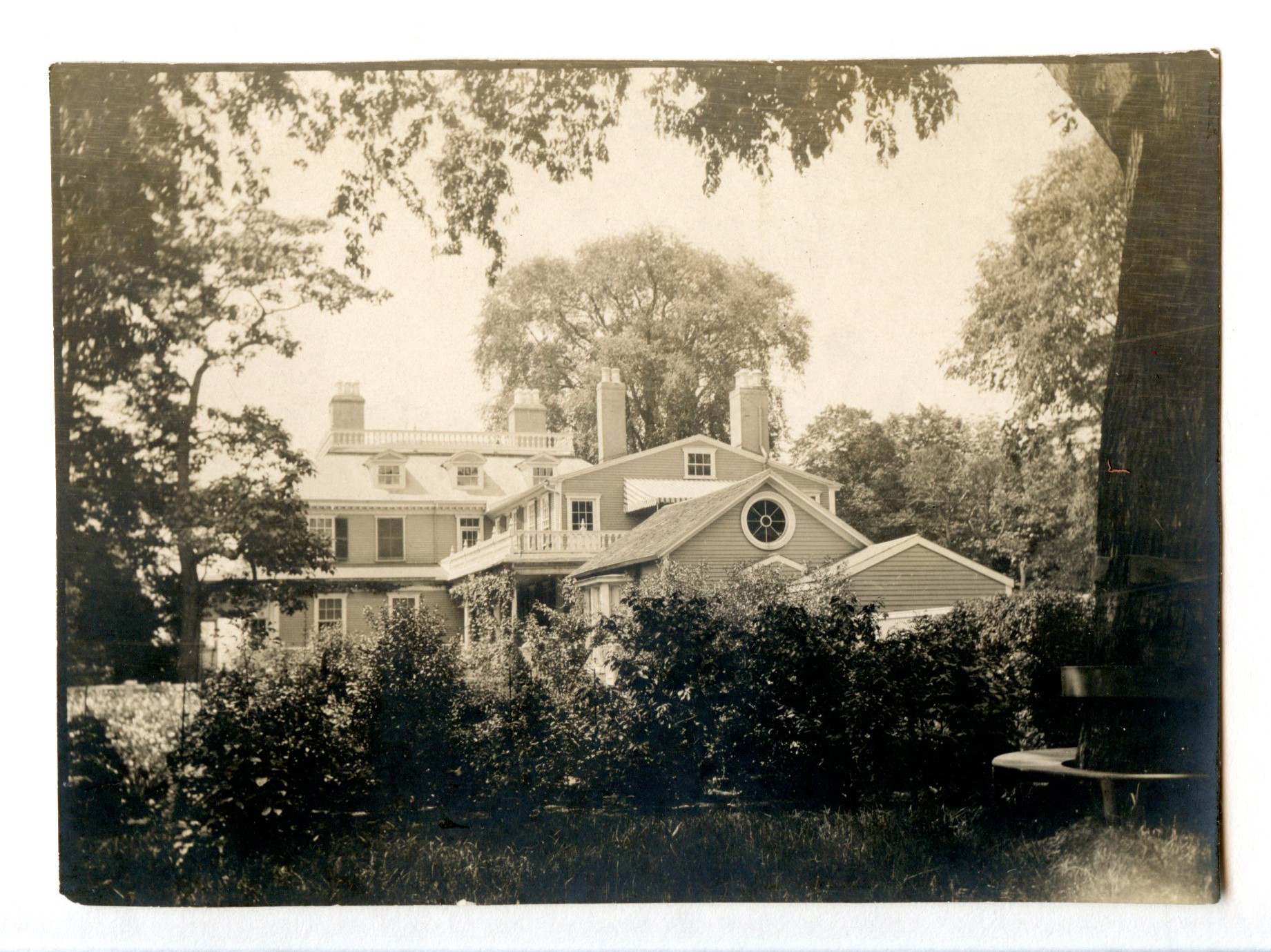 Black and white photograph of old building with many additions.