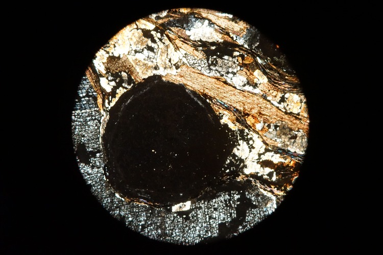 Circular microscopic image of rock structure.