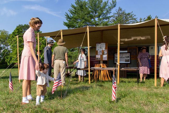 A woman and child holding hands outside of a Salvation Army camp reenactment.