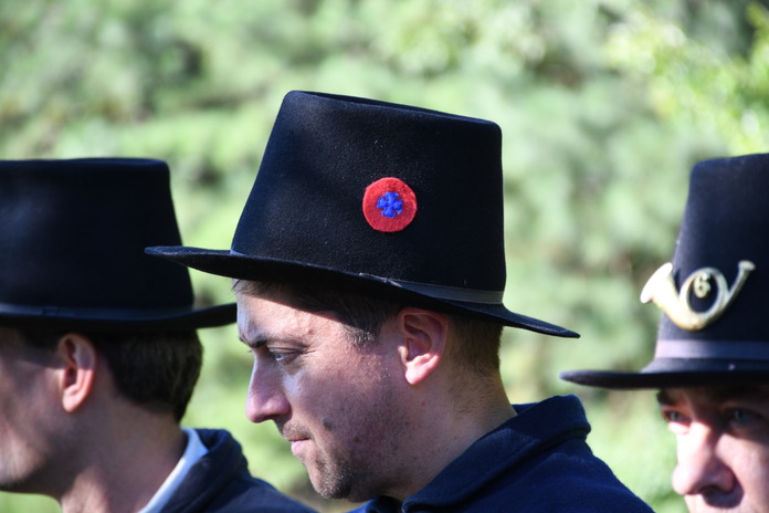 A man wearing a Hardee Hat with a badge made up of a red circle with a blue maltase cross inside it.  