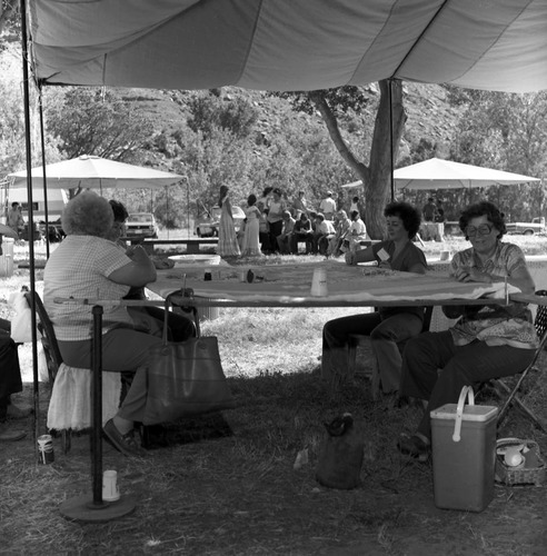 Vilo DeMille (left) and other women working on a quilt at the third annual Folklife Festival, Zion National Park Nature Center, September 7-8, 1979. Springdale elementary square dancers in background.