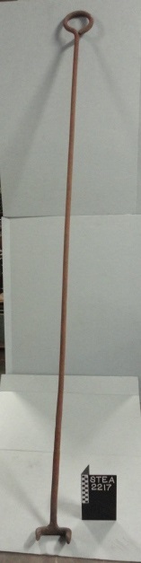 Rake. 1920-1950. Clinker rake, locomotive firebox. Round bar stock looped at one end to form a handle. At opposite end a u-shaped bar is welded at right angles to the shank. The arms of the "u" are chisel-tipped and point downward, forming a two-prong rake. Surface is pitted, rusty. 