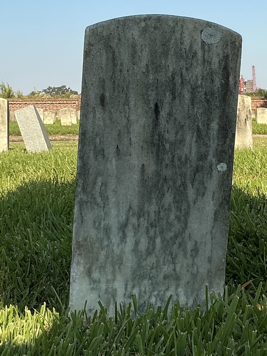Back of historic upright marble headstone with recessed shield face.